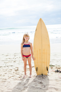 Young Girl Standing With Surfboard On Beach