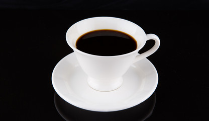 Coffee in a white cup over black background