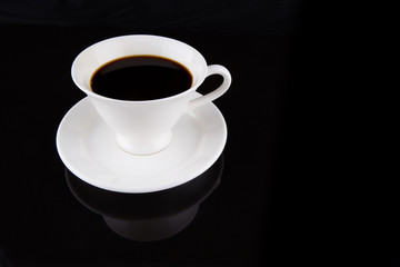Coffee in a white cup over black background