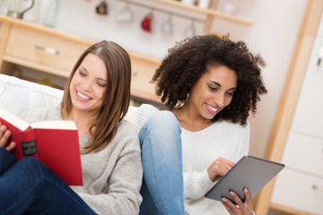 zwei freundinnen lesen mit buch und tablet-pc