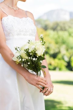 Midsection of bride holding bouquet in garden