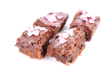 Slices of a brownie covered with chocolate and decorated with sugar hearts
