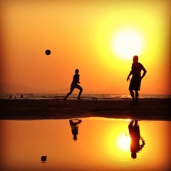 silhouettes playing football at sunset