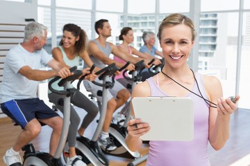 Fototapeta premium Female trainer with people working out at spinning class