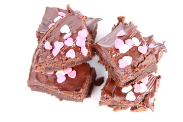 Slices of a brownie covered with chocolate and decorated with sugar hearts