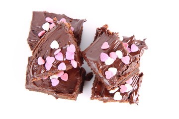 Slices of a brownie covered with chocolate and decorated with sugar hearts