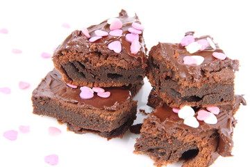 Slices of a brownie covered with chocolate and decorated with sugar hearts