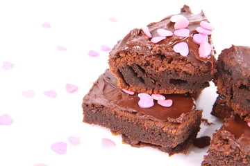 Slices of a brownie covered with chocolate and decorated with sugar hearts