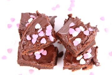 Slices of a brownie covered with chocolate and decorated with sugar hearts