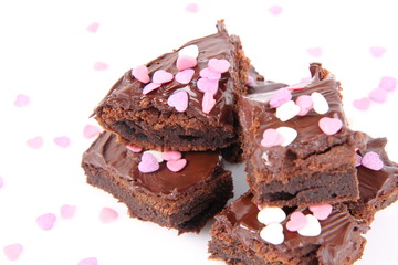 Slices of a brownie covered with chocolate and decorated with sugar hearts
