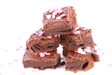 Slices of a brownie covered with chocolate and decorated with sugar hearts