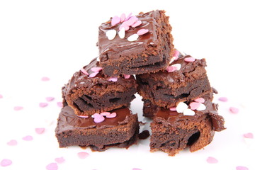 Slices of a brownie covered with chocolate and decorated with sugar hearts