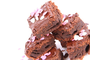 Slices of a brownie covered with chocolate and decorated with sugar hearts