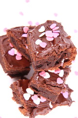 Slices of a brownie covered with chocolate and decorated with sugar hearts