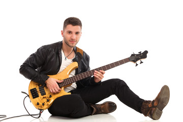 Obraz premium Male guitarist sitting on the floor.