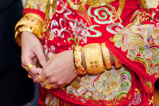 Numerous golden wedding bangles on Chinese bride