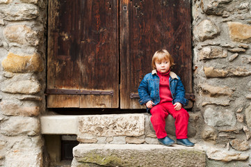 Adorable toddler boy sitting on steps outdoors