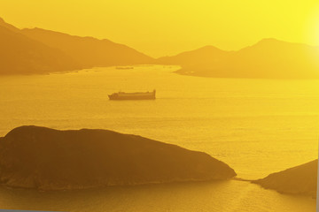 Sunset ocean along mountains with moving ships