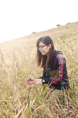 Naklejka na ściany i meble Asian woman in sunset grasses