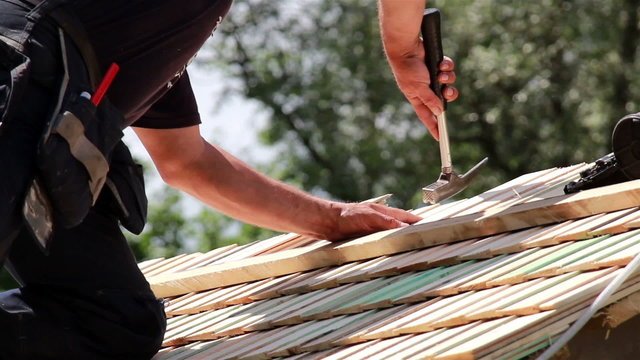 Roofers installing cedar wooden shingle roof