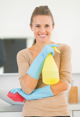 Portrait of smiling young housewife in gloves with spray bottle