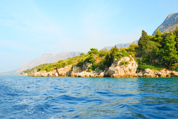 Rocky cliffs coast with green trees and deep blue sea