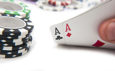 Man holding par of aces in front of poker chips and euro bills
