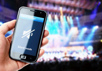 Hand holding smartphone with mute sound during concert