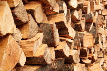 Background of dry chopped firewood logs stacked up on top of