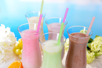 Milk shakes with fruits on table on light blue background