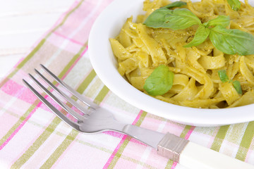 Delicious pasta with pesto on plate on table close-up
