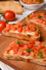 Delicious bruschetta with tomatoes on cutting board close-up