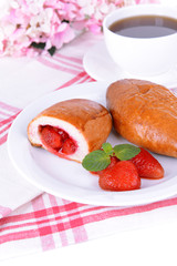 Fresh baked pasties with strawberries on plate on table