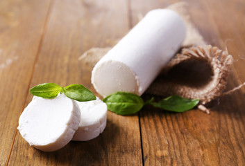 Tasty bushe cheese with basil, on wooden table