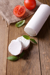 Tasty bushe cheese with basil and tomato, on wooden table