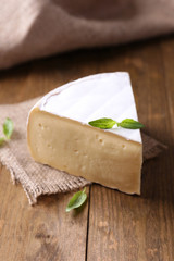 Tasty Camembert cheese with basil, on wooden table