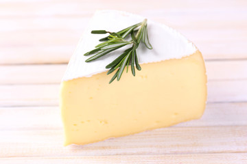 Tasty Camembert cheese with rosemary, on wooden table