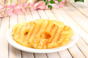 Juicy grilled pineapple on plate on table close-up
