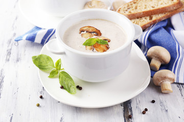Mushroom soup in white pots, on napkin, on wooden background