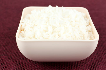 Cooked rice in bowl on red background