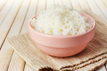 Cooked rice in bowl on wooden background