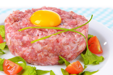 Delicious steak tartare with yolk on plate on table close-up