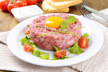 Delicious steak tartare with yolk on plate on table close-up