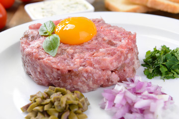 Delicious steak tartare with yolk on plate on table close-up
