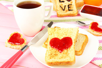 Delicious toast with jam and cup of tea on table close-up