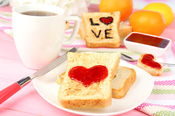 Delicious toast with jam and cup of tea on table close-up