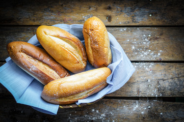 Bread rolls in the basket on rustic wooden background