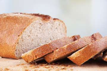 Sliced bread on wooden board on bright background