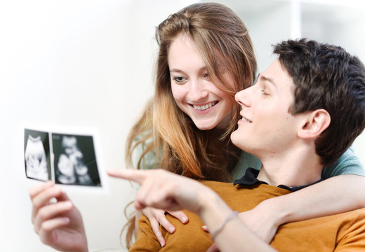 Beautiful couple watching with emotion ultrasound pictures of th