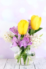 Flowers in vase on table on bright background